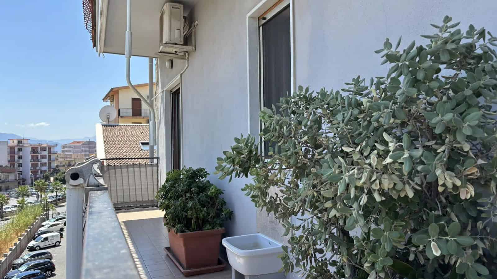 Balcone di un appartamento con piante verdi e vista sulla città di Milazzo, Sicilia.