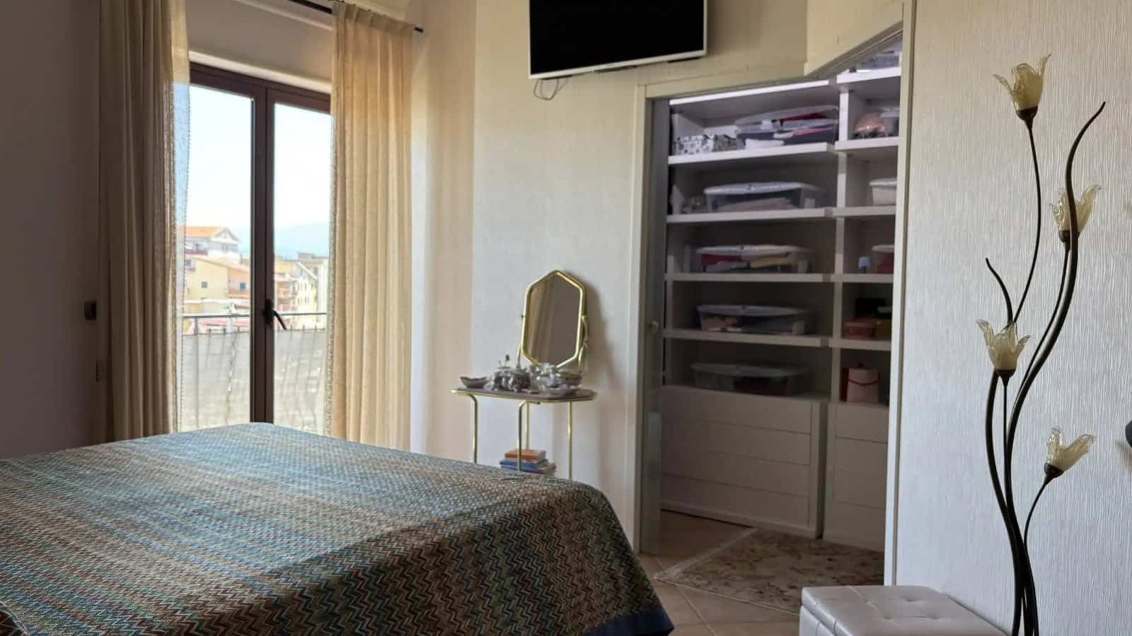 Camera rivolta verso una camera da letto con letto, armadio e balcone con vista sulla città di Milazzo.