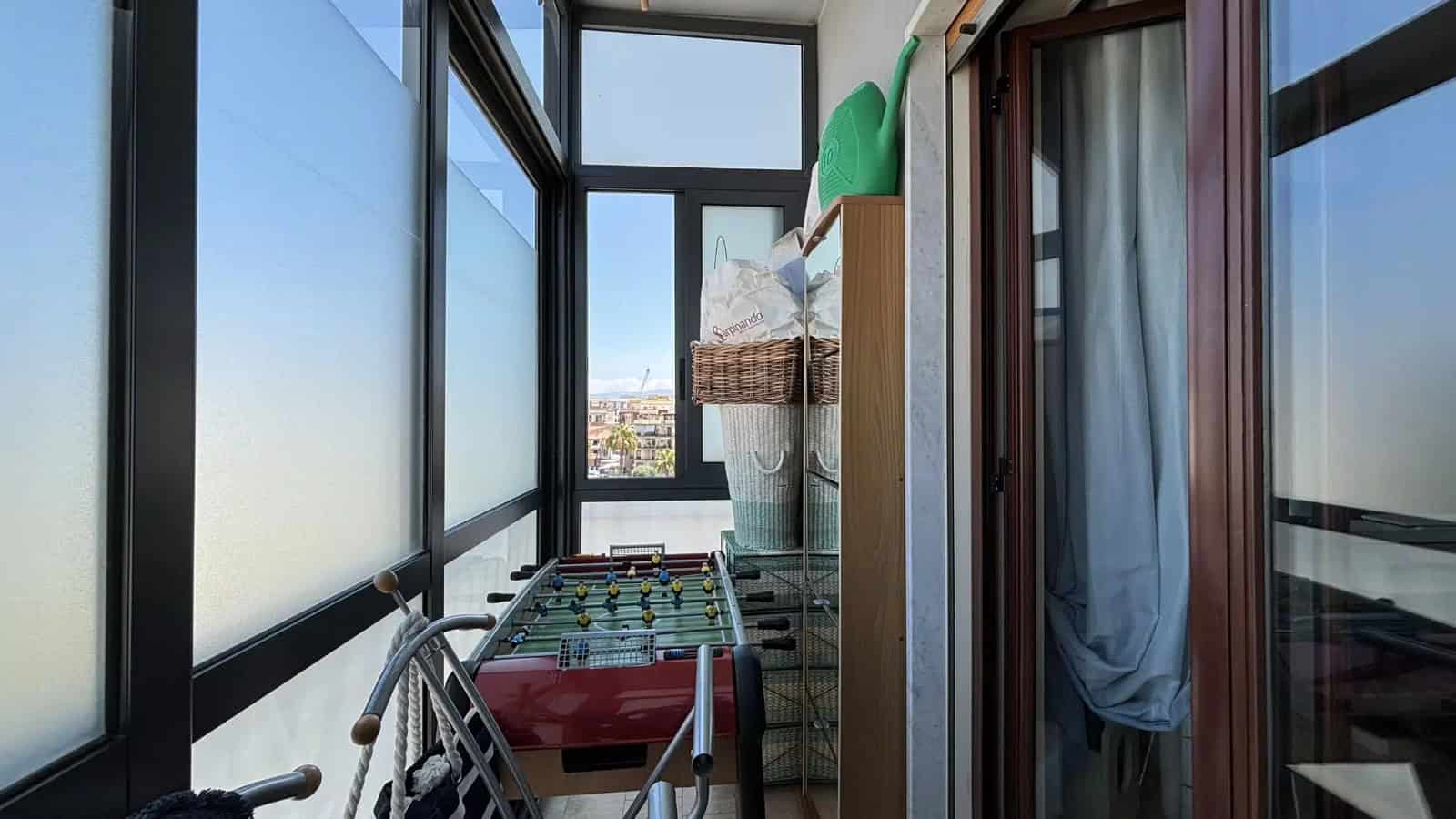 Balcone di un appartamento con vista panoramica sulla città di Milazzo, con giochi e oggetti vari.