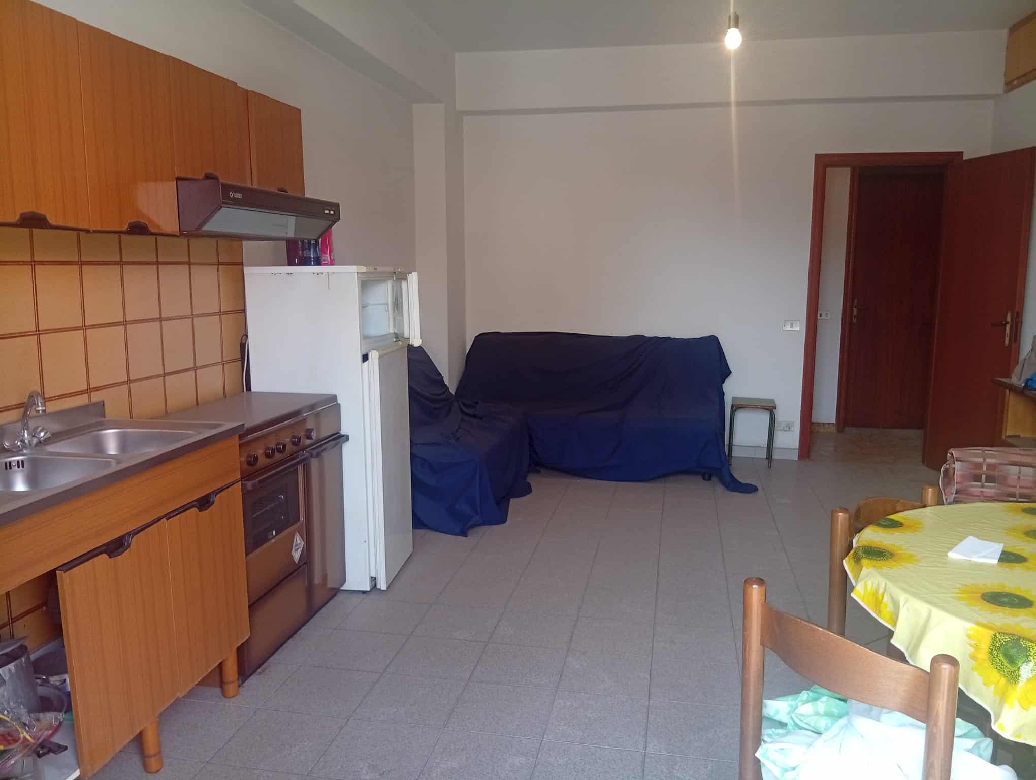 Interno di un appartamento in vendita a Falcone, con cucina, divano coperto e zona pranzo.