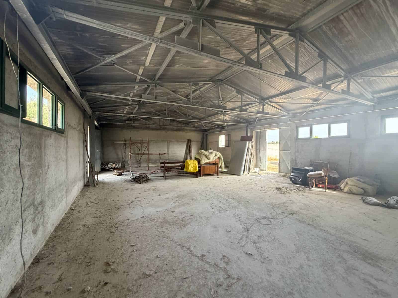 Interno di un capannone industriale con struttura in acciaio e pareti in cemento, pronto per essere ristrutturato o utilizzato.