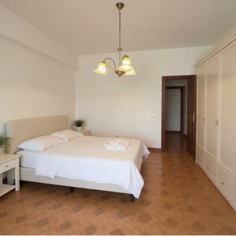 Camera da letto luminosa con letto matrimoniale, armadio grande e lampadario a soffitto in stile classico.