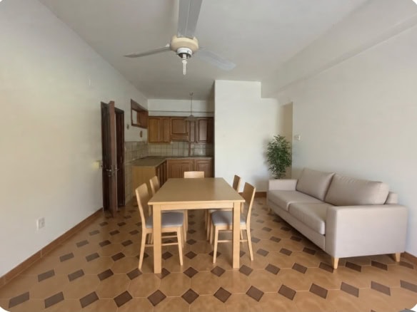 Interno soggiorno con tavolo da pranzo, divano e cucina in stile semplice e funzionale.