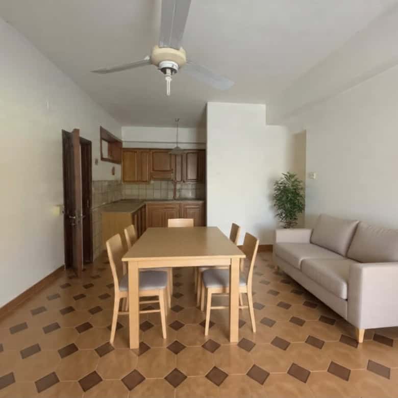 Interno soggiorno con tavolo da pranzo, divano e cucina in stile semplice e funzionale.