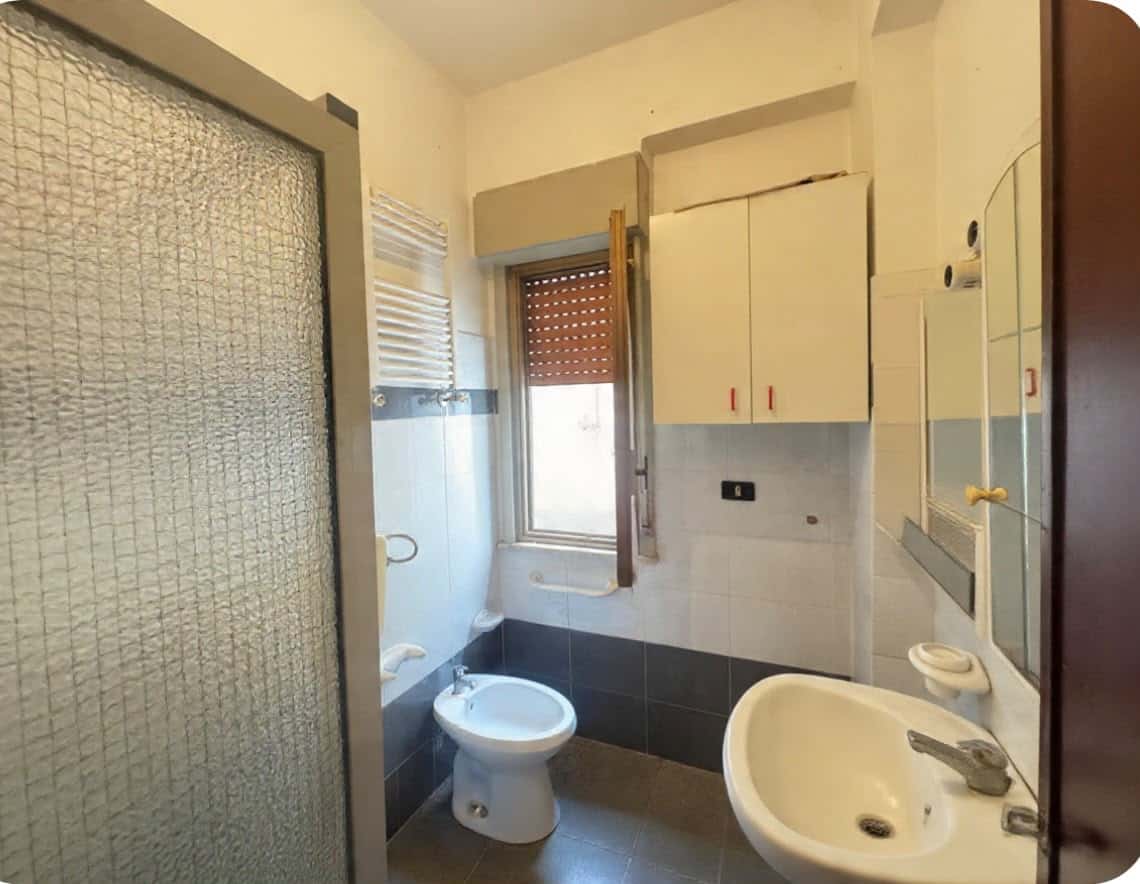 Bagno con finestra, lavabo, bidet e armadietto, in stile semplice e funzionale.