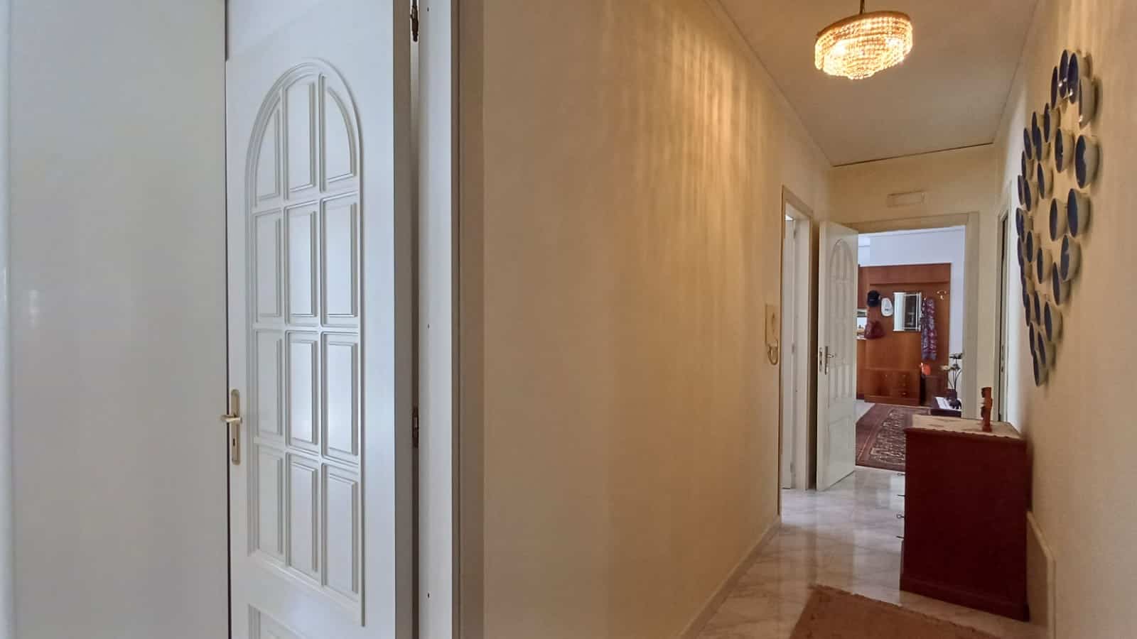 Ingresso di un appartamento con porta bianca e corridoio luminoso in stile classico.
