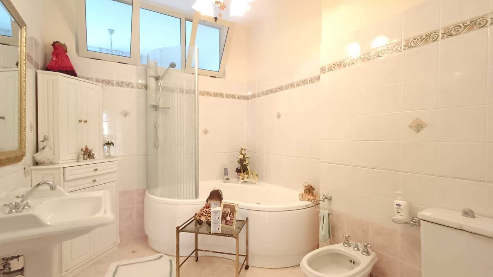 Bagno spazioso con vasca idromassaggio, doccia separata e lavabo in stile classico, illuminato da luce naturale dalle finestre.