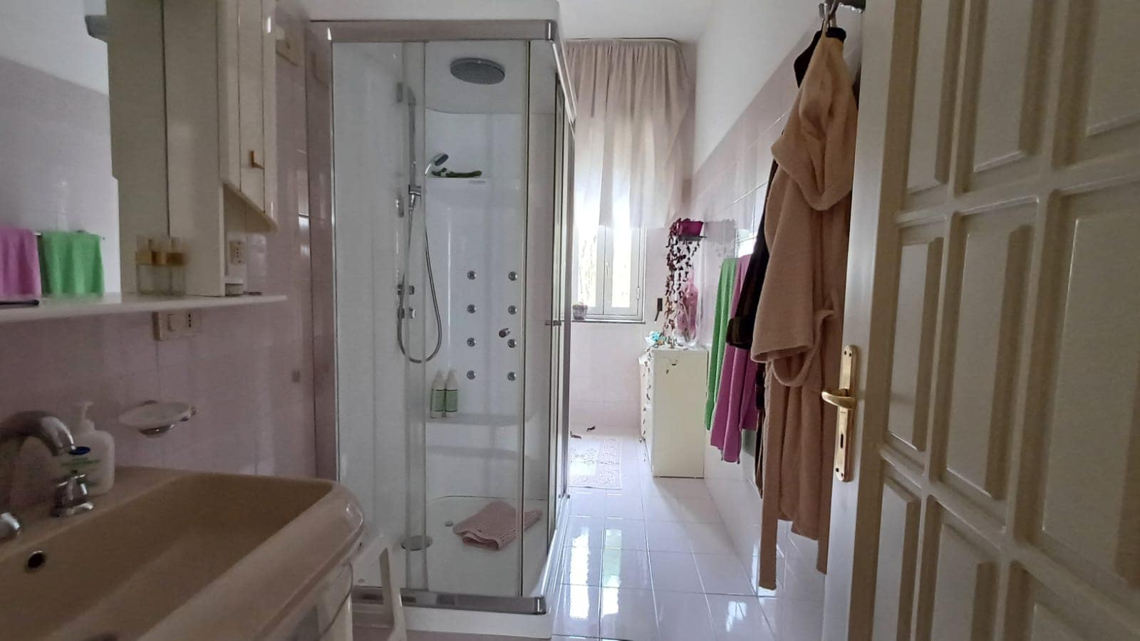 Bagno di un appartamento in vendita a Capo d'Orlando con doccia, lavabo e tende colorate.