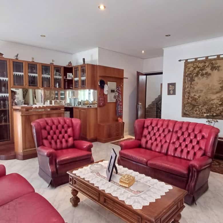 Salotto spazioso con divani rossi, parete con arazzo e mobile in legno con vetrine, ambiente luminoso e accogliente.