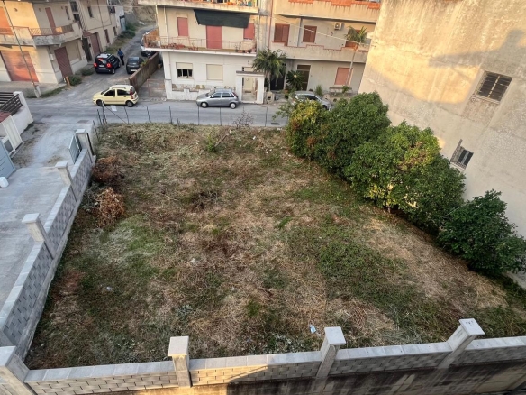 Spazio esterno di un cortile condominiale con prato e arbusti, vista dall'alto in un quartiere residenziale.