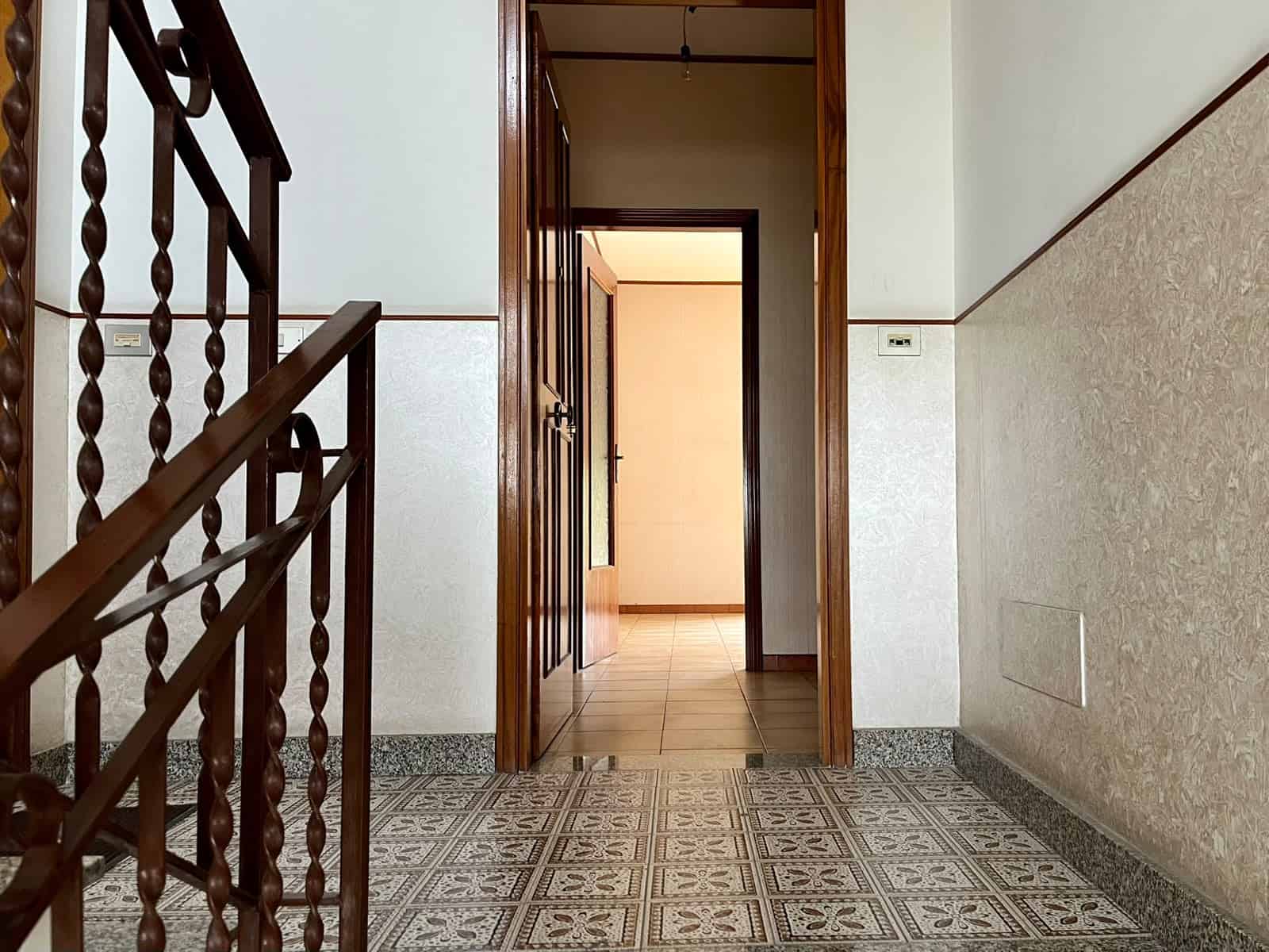 Ingresso di un appartamento in vendita in via Don Silvio Cucinotta, Pace del Mela, con pavimento in piastrelle decorative e porta in legno.