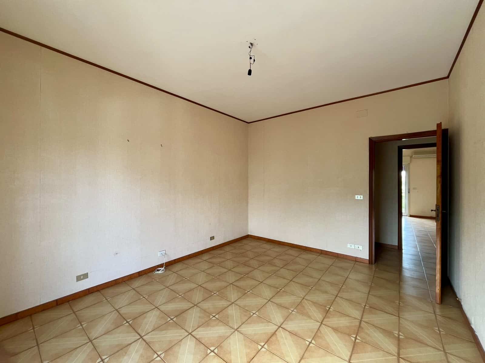 Ampio soggiorno vuoto in appartamento in vendita a Pace del Mela, con pareti beige e pavimento in ceramica.