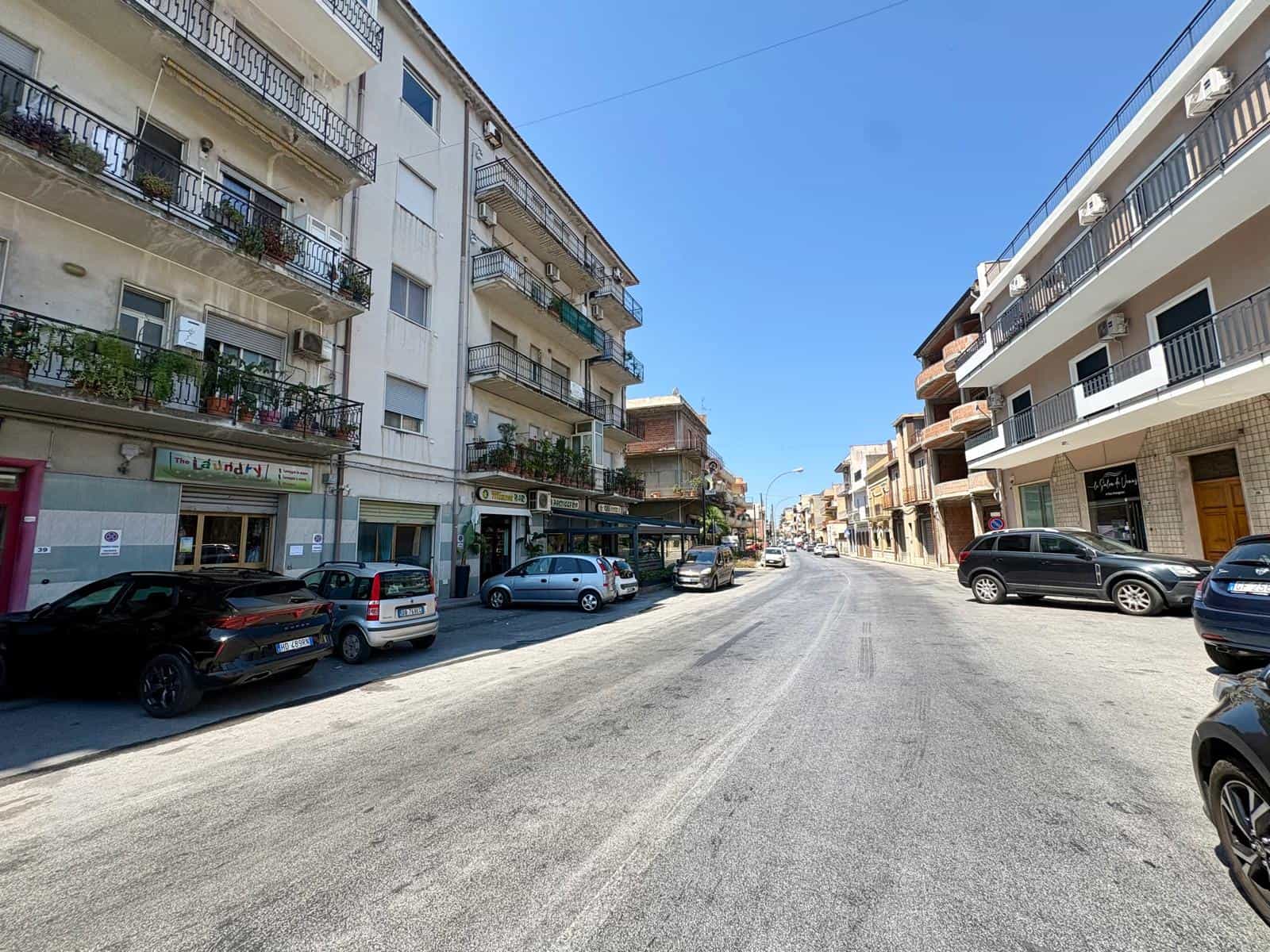Vista della strada principale in Via Nazionale 45 a Giammoro, con edifici residenziali e parcheggi.
