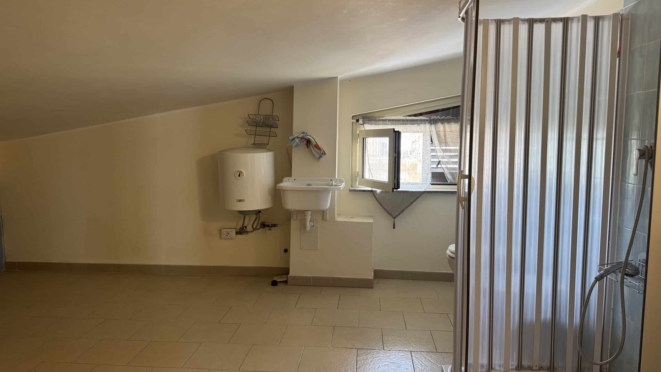 Interno di un appartamento in affitto a Milazzo con pareti bianche e finestra.