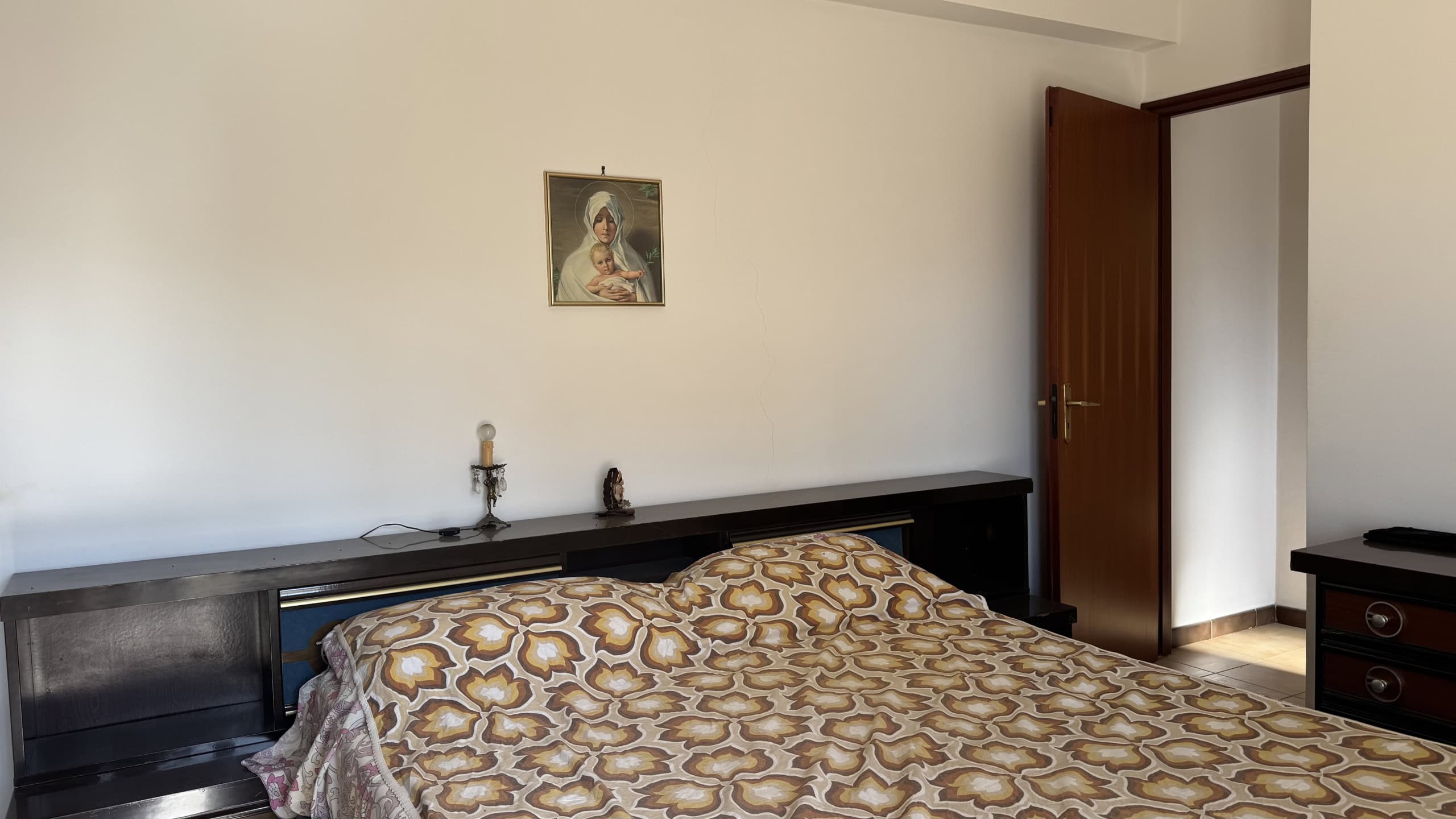 Interno di una camera da letto luminosa con letto matrimoniale e decorazioni semplici, situata in Via Nazionale 35, Falcone, Me.