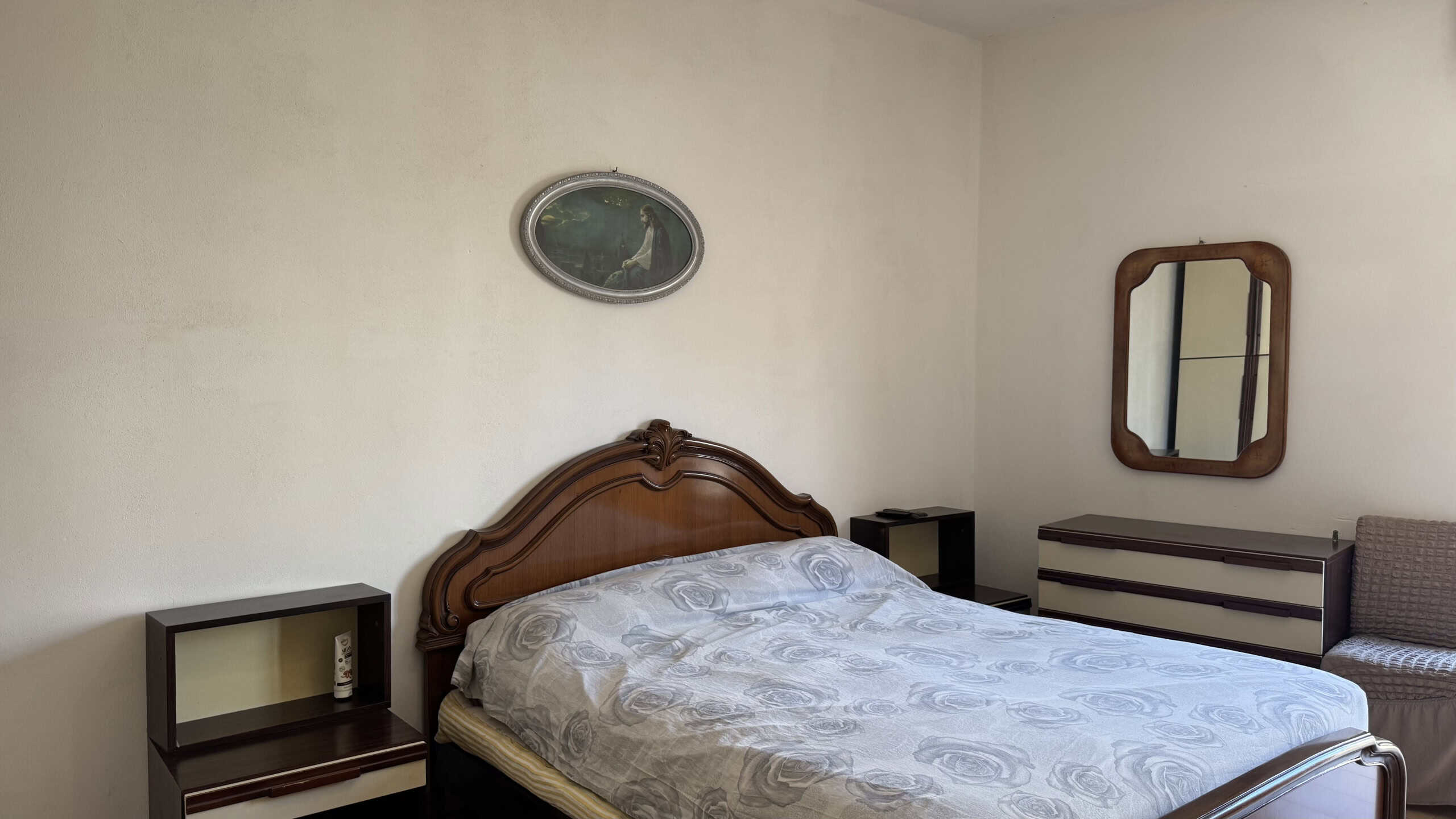 Camera da letto con letto matrimoniale, specchio e mobili in stile classico, ambiente luminoso e accogliente.