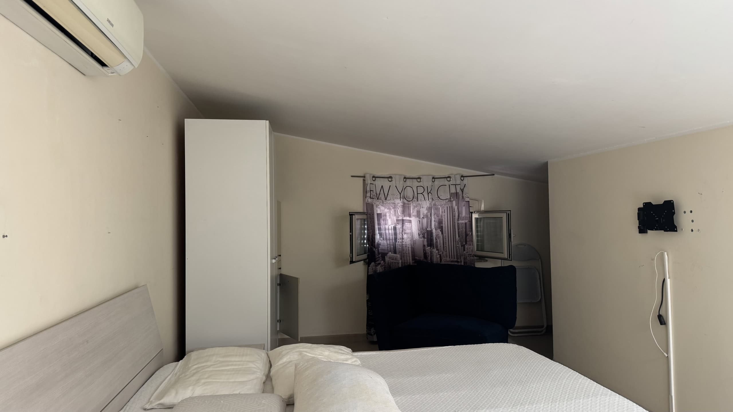 Interno di un appartamento in affitto a Milazzo, con letto matrimoniale e soggiorno con divano e finestra.