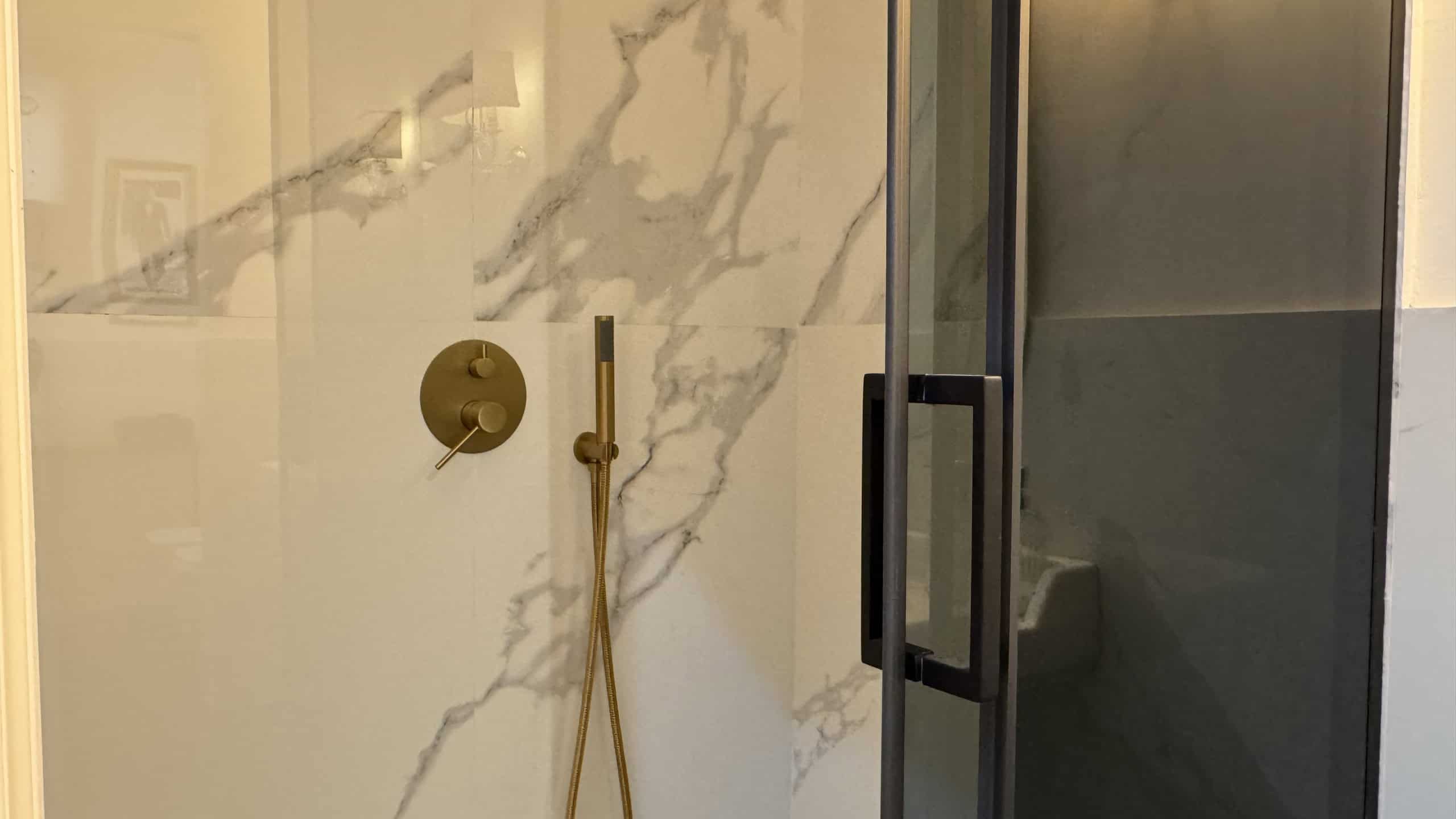 Doccia moderna con pareti in vetro e piastrelle effetto marmo bianco e grigio in appartamento in vendita a Me.