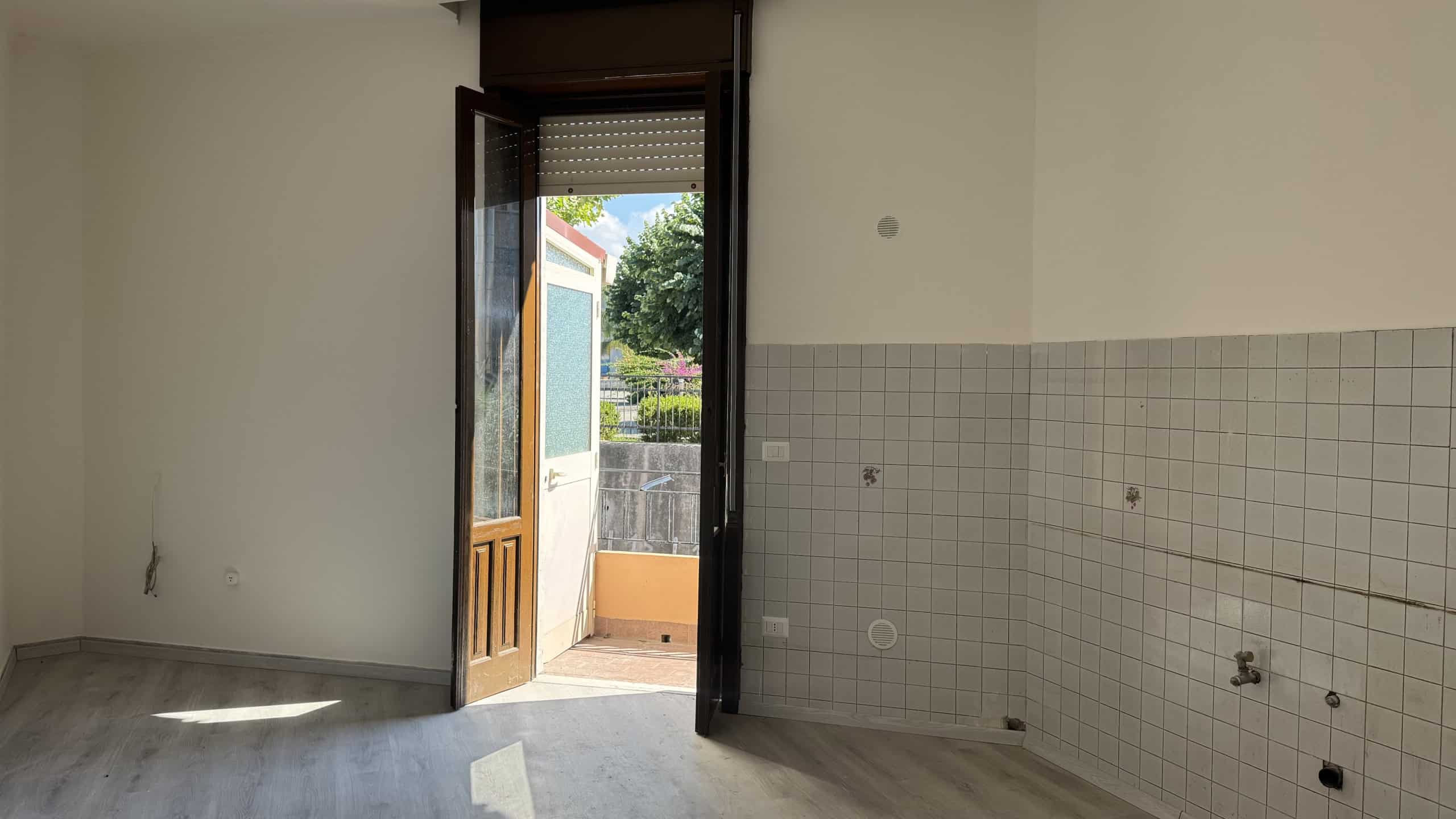 Interno di una casa semindipendente in vendita a Venetico, con porta aperta che dà su un balcone esterno e pareti con piastrelle.