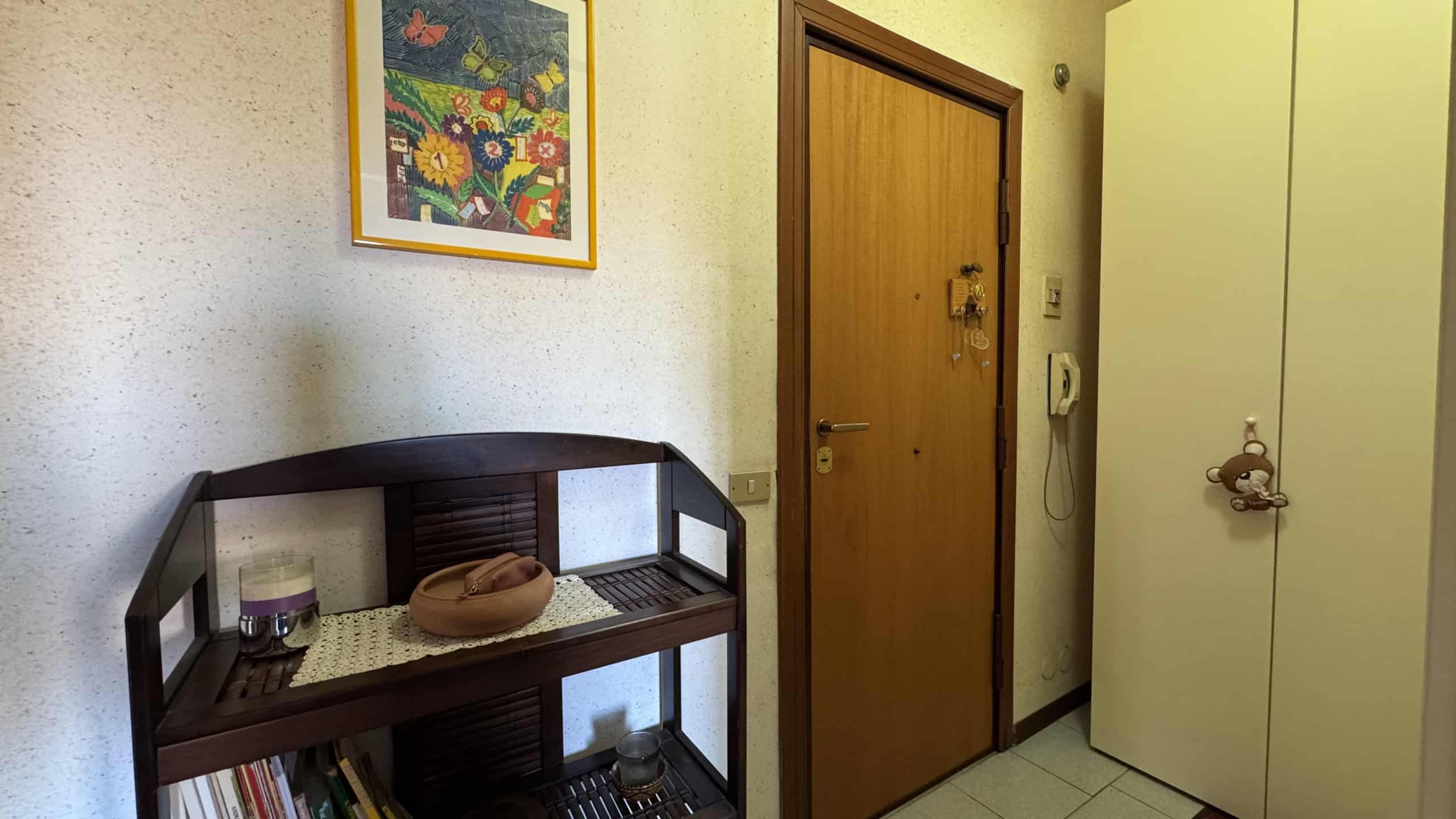 Ingresso di un appartamento con porta in legno e armadio bianco vicino alla parete.
