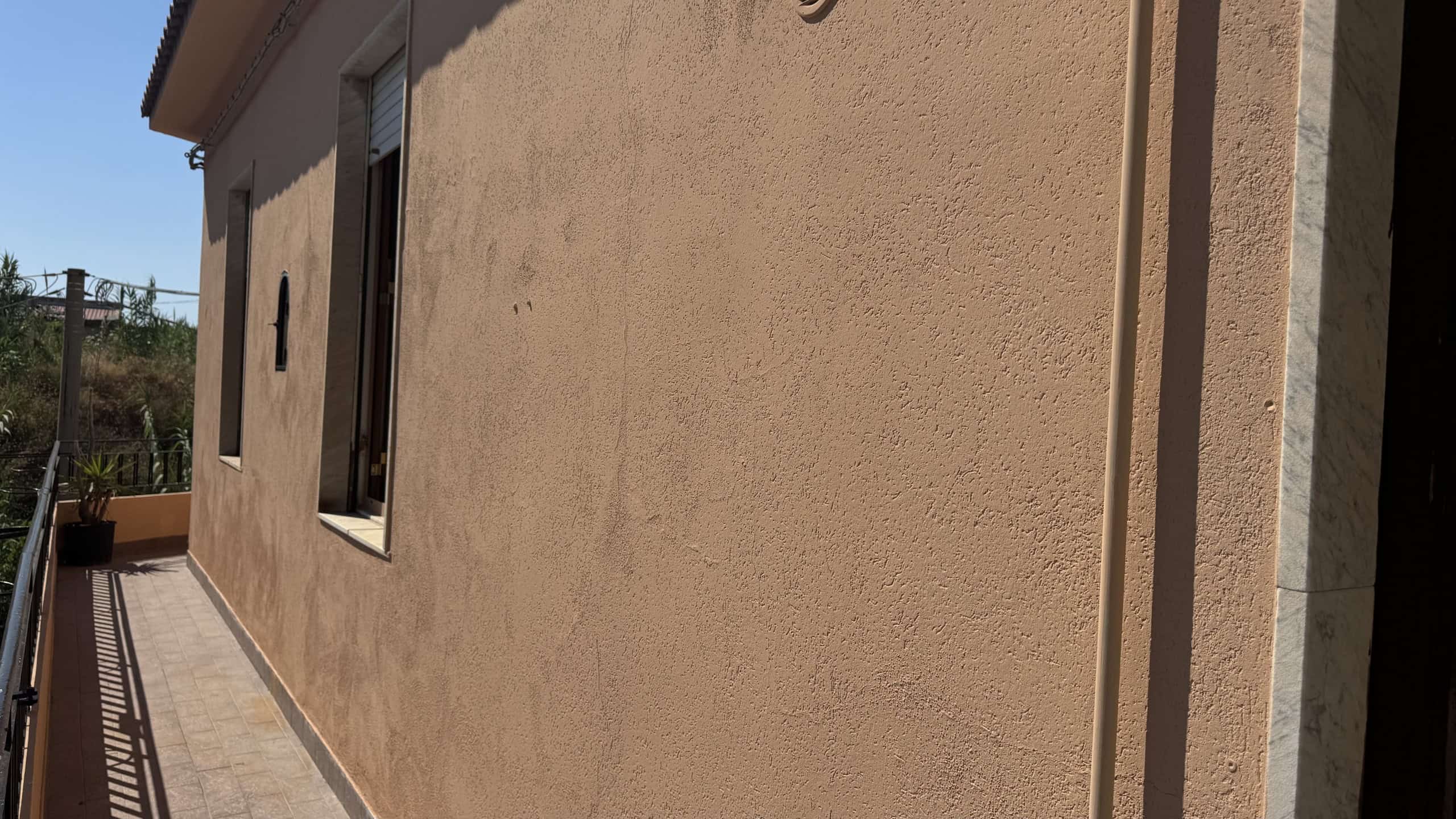 Facciata esterna di una casa semindipendente in vendita a Venetico, con pareti beige e finestra.