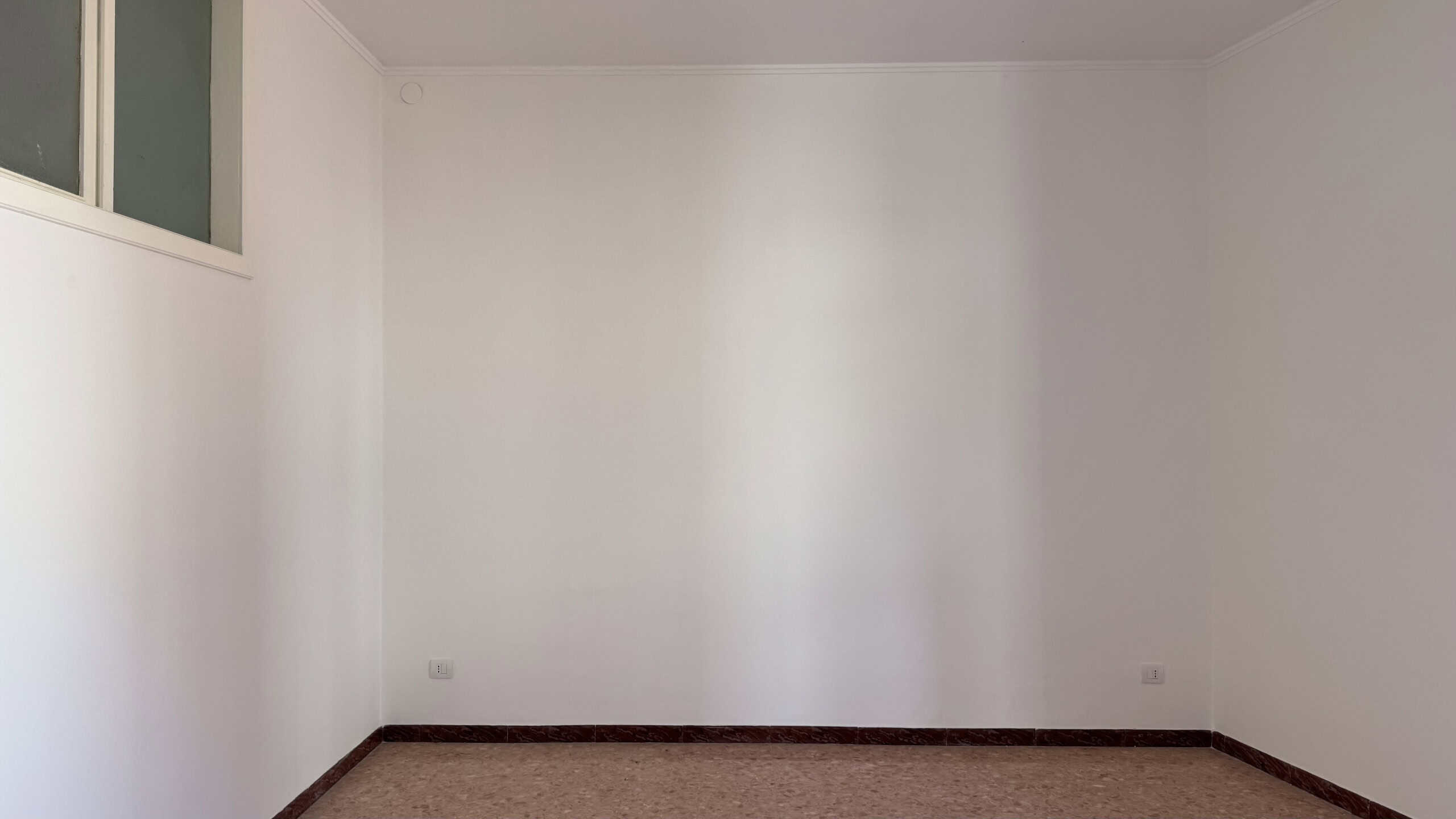 Interno di una casa semindipendente in vendita a Venetico, stanza luminosa con pareti bianche e pavimento in piastrelle scure.