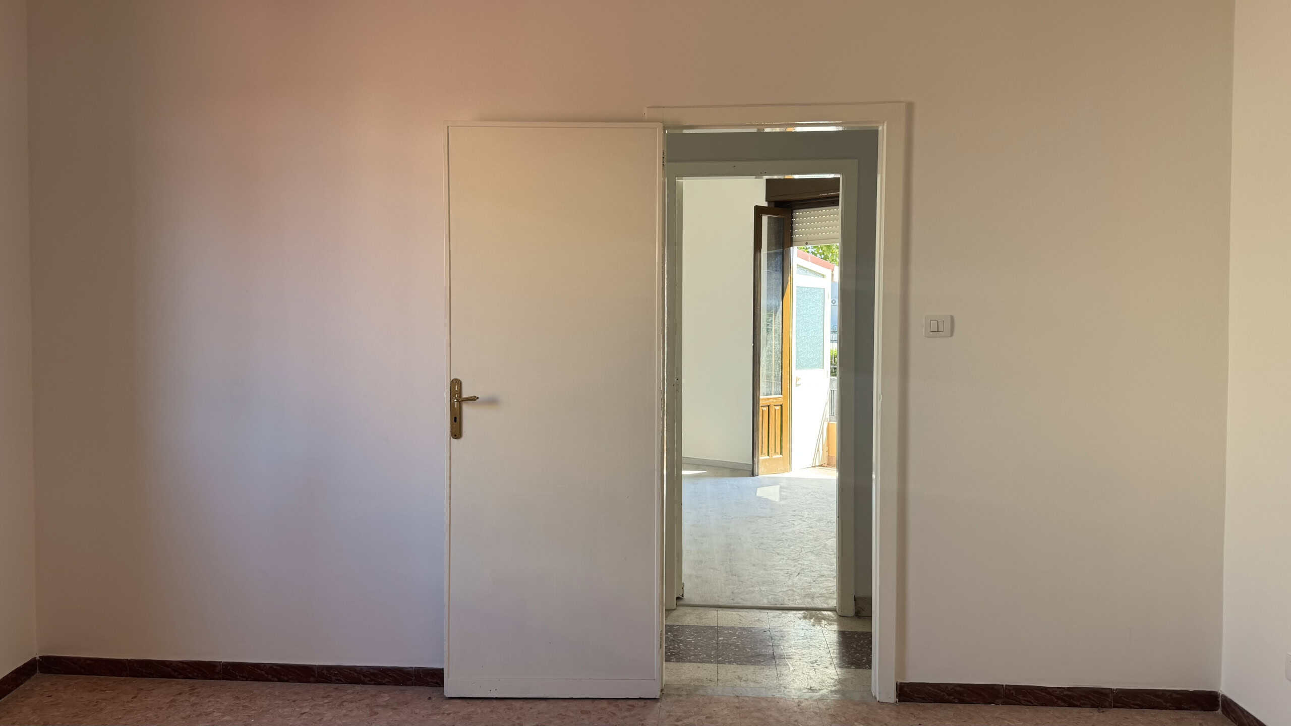 Interno di una casa semindipendente in vendita a Venetico, vista da una stanza con porta aperta verso un'altra stanza luminosa.