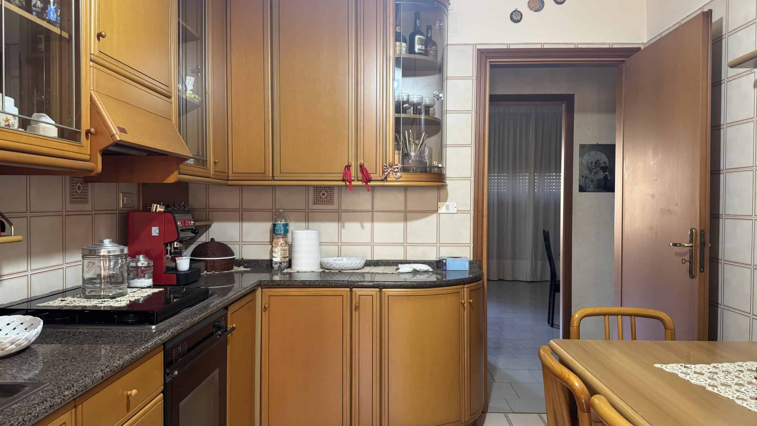 Cucina abitabile con mobili in legno, piano di lavoro in granito e elettrodomestici moderni, in un appartamento a Messina.
