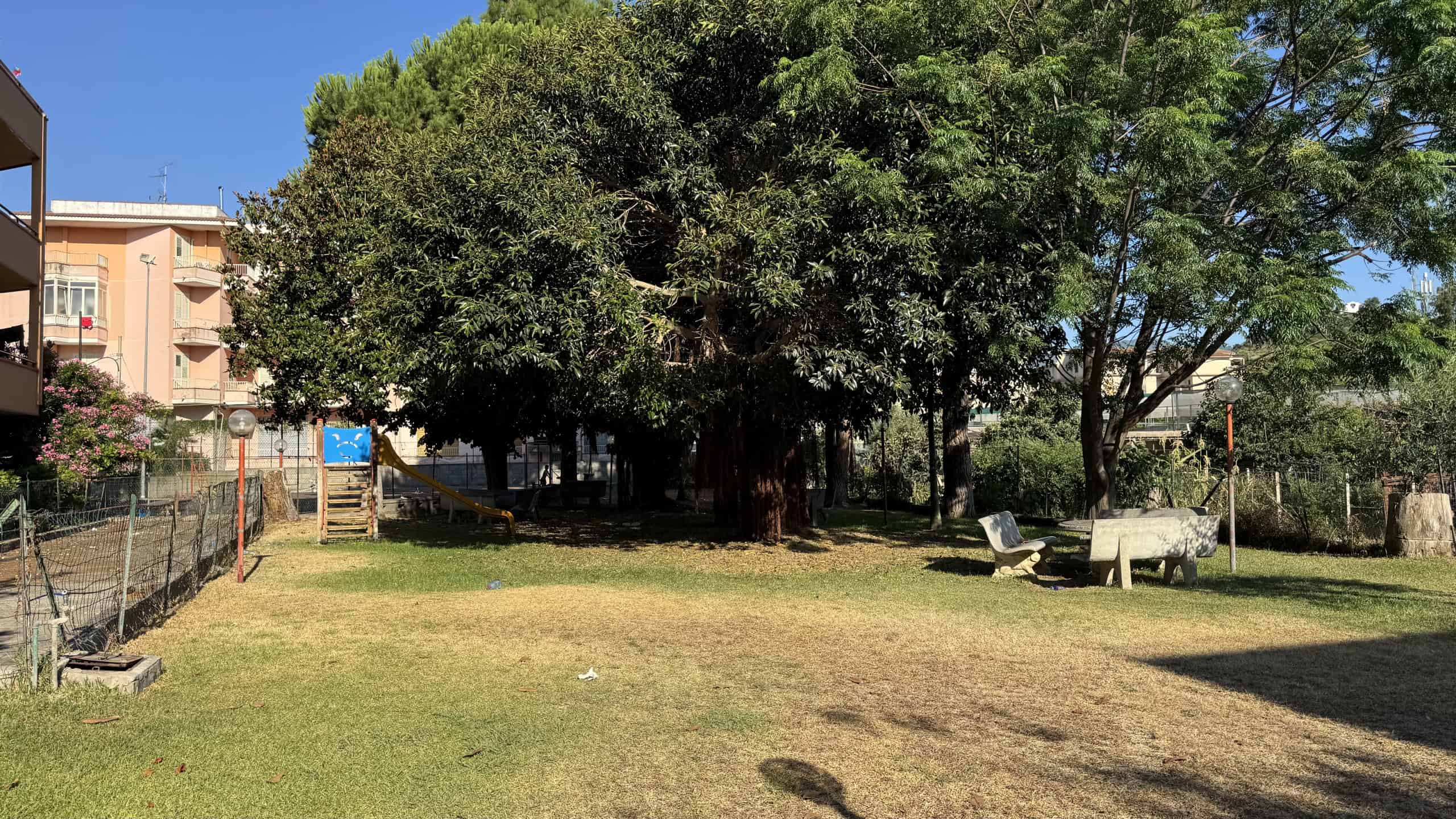 Area verde con grandi alberi e panchine, ideale per relax all'aperto a Falcone, Me.