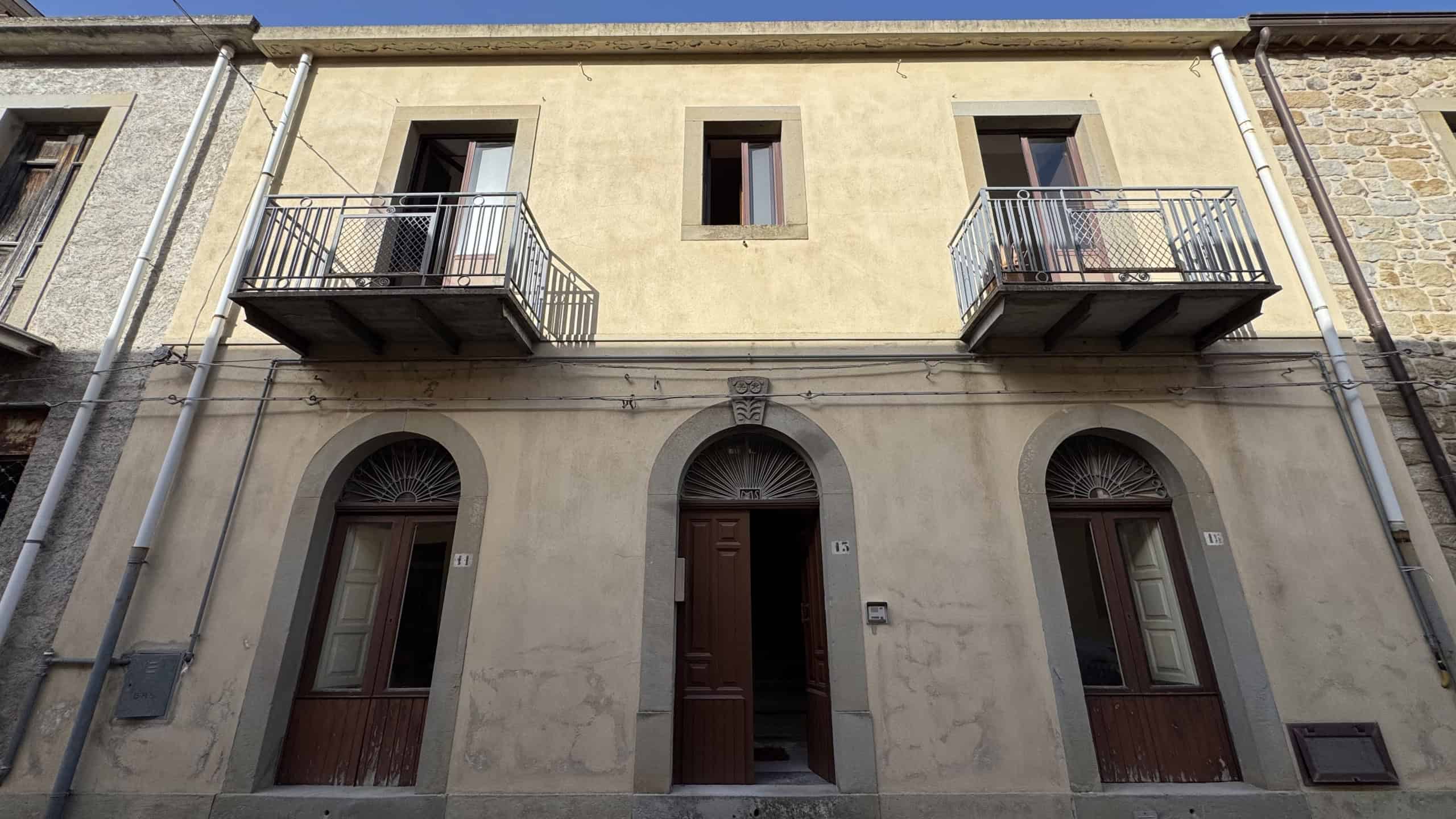 Facciata di una casa indipendente in vendita a Castell'Umberto, con due balconi e porte d'ingresso in stile classico.