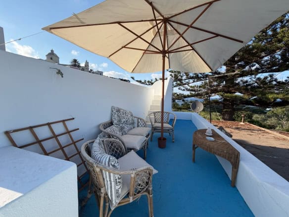 Terrazza con sedie, ombrellone e vista su Lipari, Sicilia, in un ambiente esterno soleggiato.