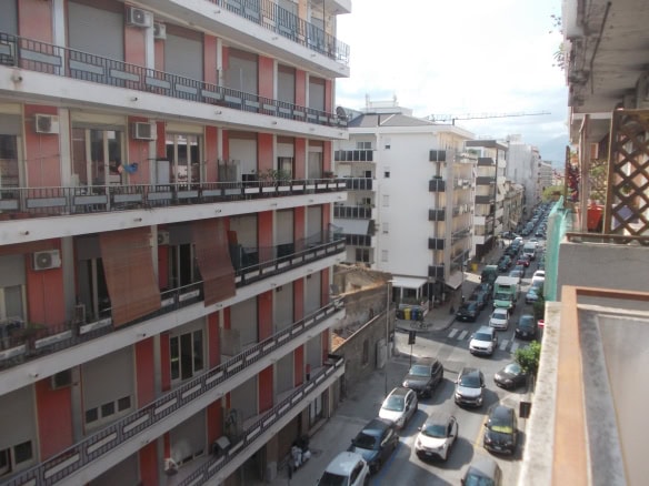 Immagine di un condominio nel centro di Milazzo con strada trafficata e edifici residenziali.