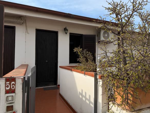 Esterno di un appartamento in vendita a Furnari con balcone e giardino, vista su strada e cielo sereno.